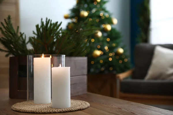Hořící svíčky a jedle větve na dřevěném stole v místnosti zdobené k Vánocům — Stock fotografie