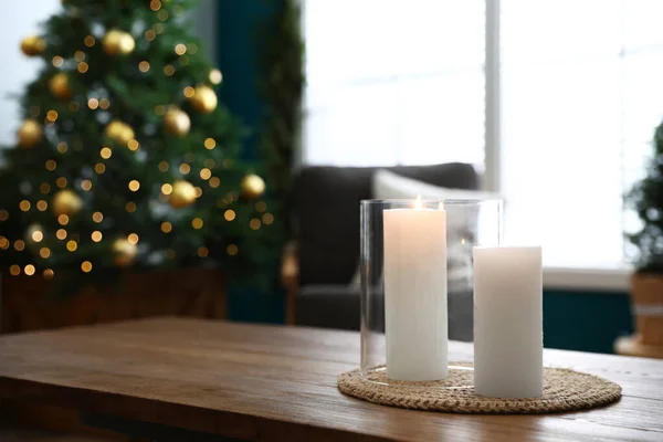 Hořící svíčky na dřevěném stole v místnosti zdobené k Vánocům — Stock fotografie