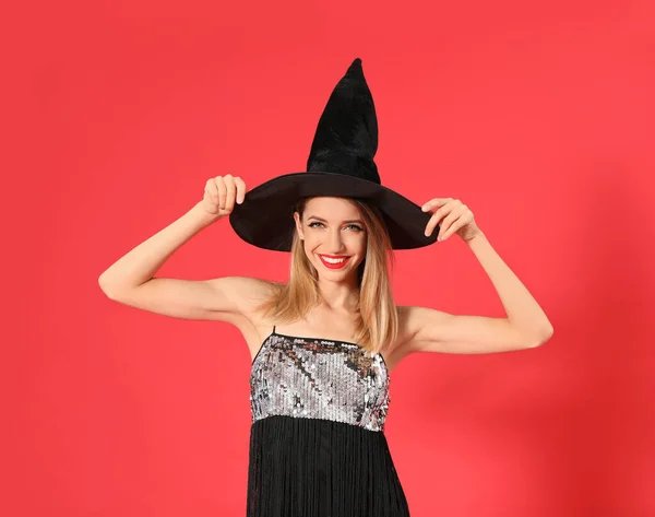 Hermosa mujer joven con traje de bruja para la fiesta de Halloween sobre fondo rojo —  Fotos de Stock