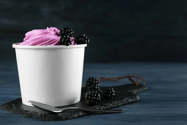 Cup with tasty frozen yogurt and blackberries on blue wooden table. Space for text — Stock Photo, Image