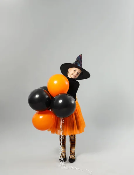 Aranyos kislány léggömbök visel Halloween jelmez szürke háttér — Stock Fotó