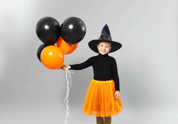 Cute little girl z balonami na sobie kostium Halloween na szarym tle — Zdjęcie stockowe