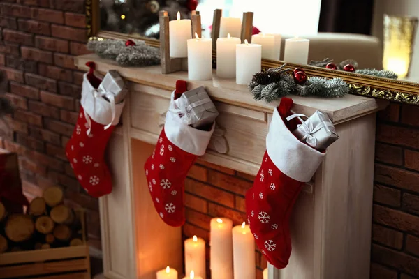 Chimenea decorativa con medias de Navidad y regalos en el interior de la habitación con estilo —  Fotos de Stock