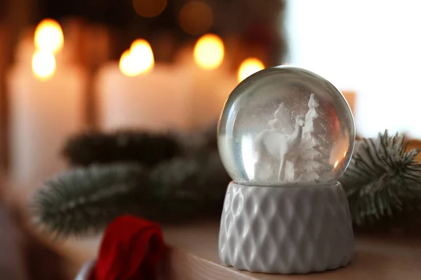 Snow globe on wooden table against blurred background. Space for text
