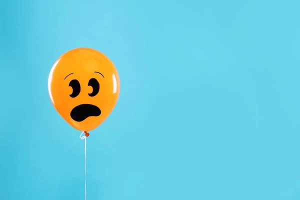 Πορτοκαλί μπαλόνι με σχέδιο του φοβάται το πρόσωπο σε μπλε φόντο, χώρος για κείμενο. Αποκριάτικο πάρτι — Φωτογραφία Αρχείου
