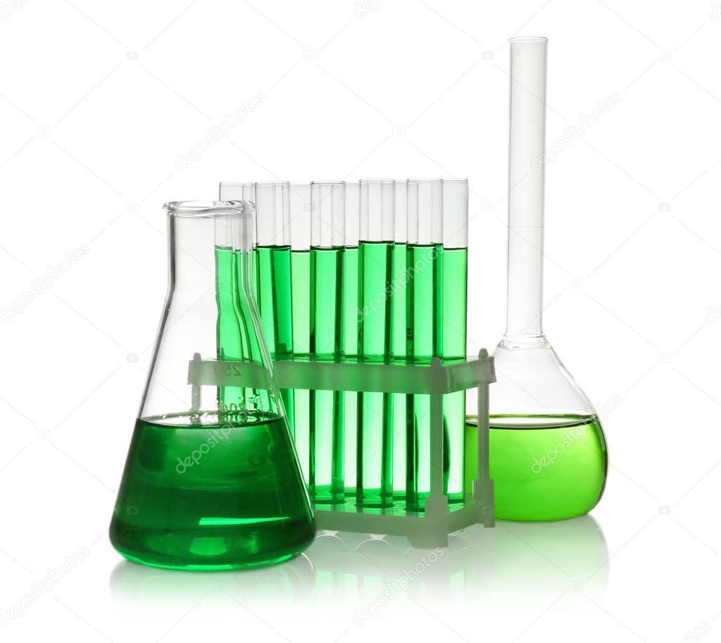 Laboratory glassware with green liquid on white background