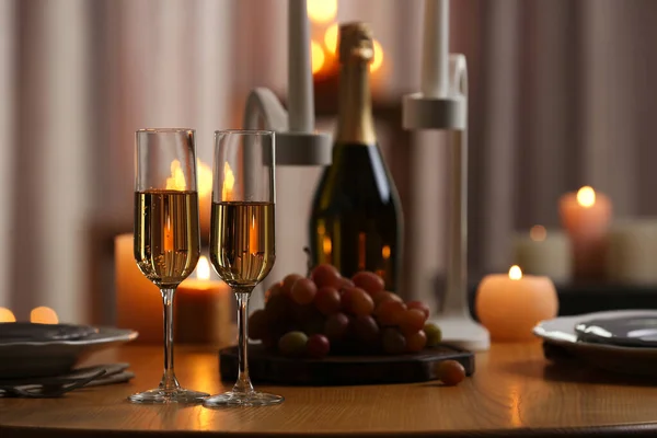 Glas champagne op houten tafel tegen wazig brandende kaarsen — Stockfoto