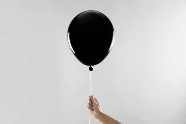 Mulher segurando balão preto para festa de Halloween no fundo cinza claro, close-up — Fotografia de Stock