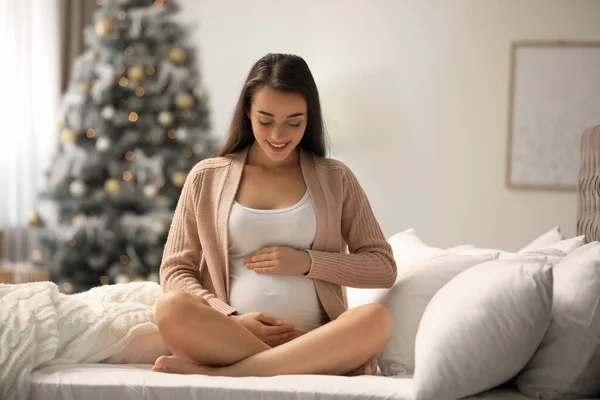 Mulher grávida feliz na cama no quarto decorado para o Natal. Bebê esperado — Fotografia de Stock
