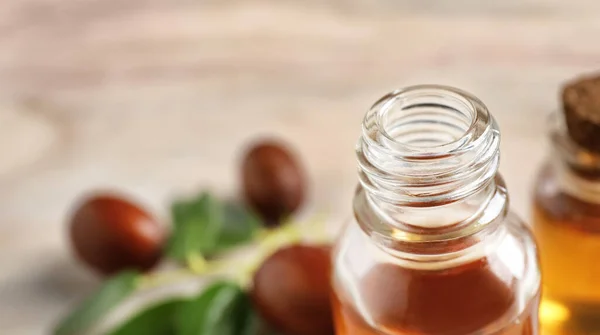 Botol kaca dengan minyak jojoba dengan latar belakang kabur, closeup. Ruang untuk teks — Stok Foto