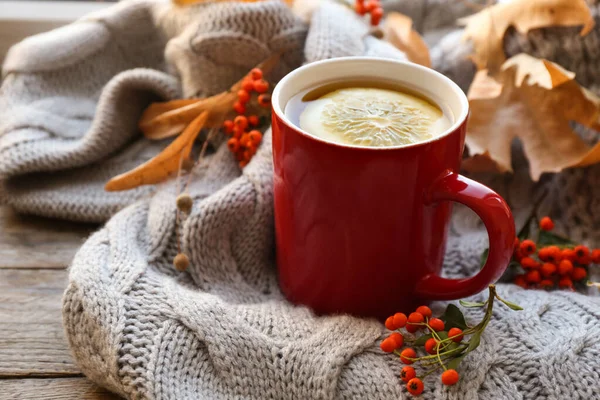Cup of hot drink, sweater and autumn leaves on wooden table. Cozy atmosphere — Stock Photo, Image
