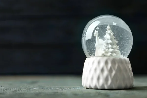 Boule à neige avec cerfs et arbres sur table en bois bleu, espace pour le texte. Saison de Noël — Photo