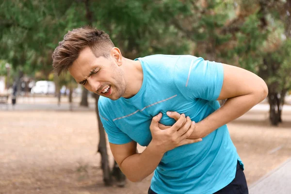 Молодий чоловік страждає від серцевого нападу під час бігу в парку — стокове фото