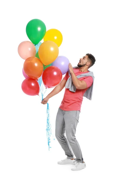 Emotional young man holding bunch of colorful balloons on white background — Stock Photo, Image