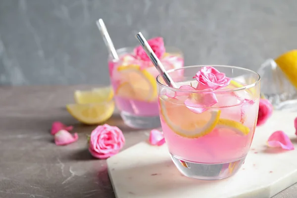 大理石のテーブルの上にレモンとバラとおいしいさわやかな飲み物 — ストック写真