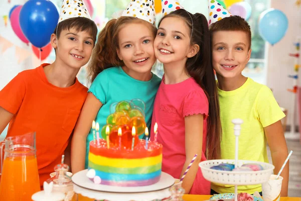 Boldog gyerekek torta közelében gyertyákkal a születésnapi party beltérben — Stock Fotó