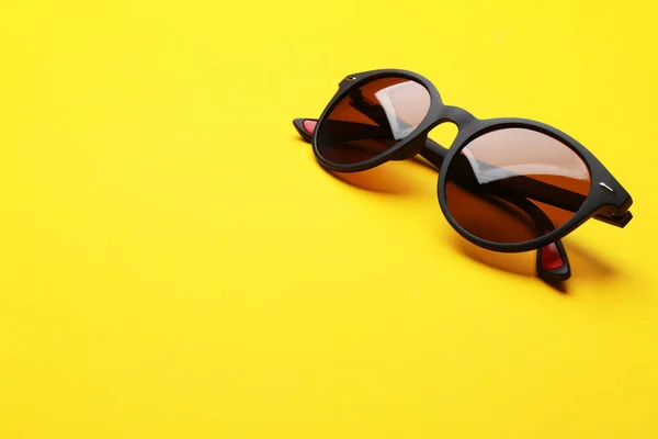 Elegantes gafas de sol sobre fondo amarillo, espacio para texto. Accesorio de moda — Foto de Stock