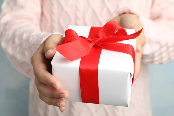 Vrouw het houden van mooie kerstcadeau op licht blauwe achtergrond, close-up — Stockfoto