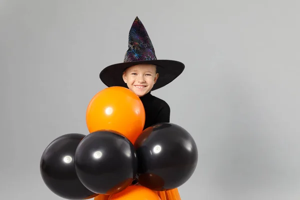 Aranyos kislány léggömbök visel Halloween jelmez szürke háttér — Stock Fotó