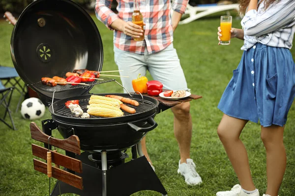 People with beverages near barbecue grill outdoors