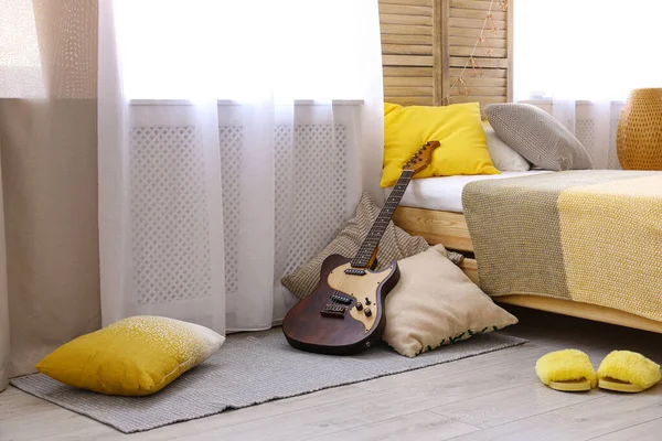 Modernes Interieur mit Gitarre und Kopfkissen in Bettnähe — Stockfoto