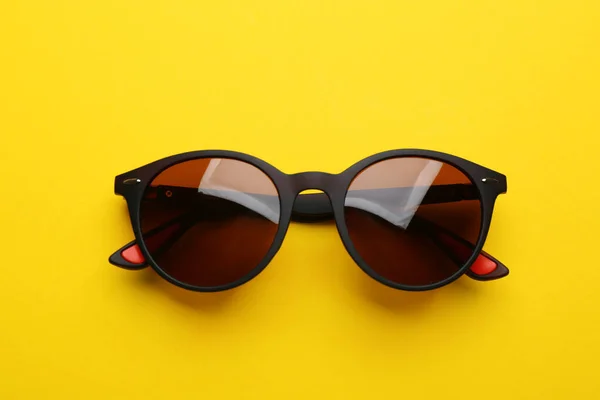 Stylish sunglasses on yellow background, top view. Fashionable accessory — Stock Photo, Image