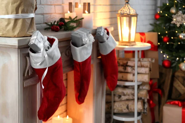 Medias rojas de Navidad con regalos en la chimenea decorativa en el interior. Interior festivo —  Fotos de Stock