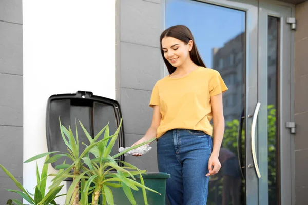 Jonge vrouw gooien plastic fles in recycling bin buitenshuis — Stockfoto