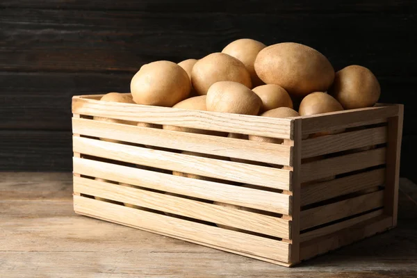 Сырой свежий органический картофель на деревянном столе на темном фоне — стоковое фото