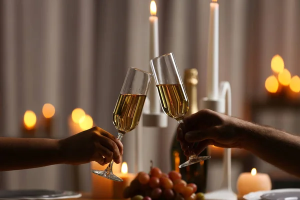 Een paar glazen champagne tegen brandende kaarsen, close-up — Stockfoto