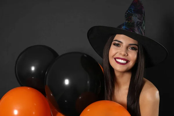 Hermosa mujer con traje de bruja con globos para la fiesta de Halloween sobre fondo negro — Foto de Stock