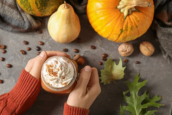 Woman holding mason jar of tasty pumpkin spice latte at grey table, top view — Stock Photo, Image