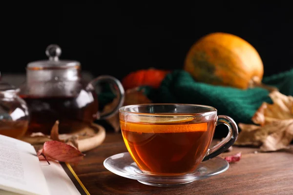 Cup of hot drink on wooden table against black background. Cozy autumn atmosphere — ストック写真