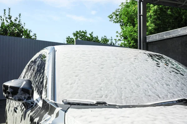 Automobile covered with foam at car wash, closeup of windshield — Stock Photo, Image