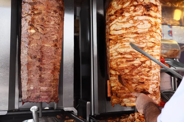 Man cutting meat from vertical rotisserie, closeup view — Stock Photo, Image