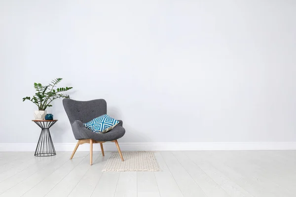 Stylish room interior with comfortable armchair and plant near white wall. Space for text — Stock Photo, Image