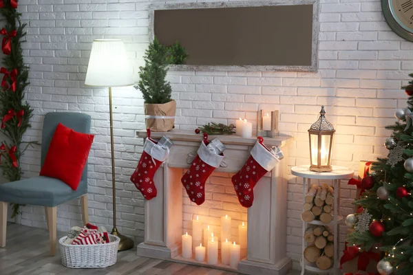 Elegante interior de Navidad con chimenea decorativa cerca de la pared de ladrillo blanco —  Fotos de Stock