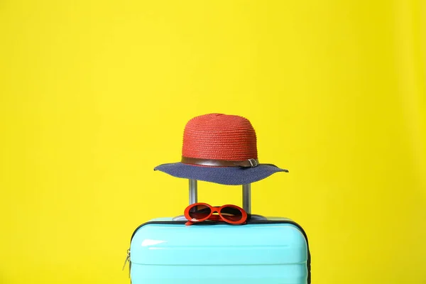 Elegante maleta azul con sombrero y gafas de sol sobre fondo amarillo — Foto de Stock