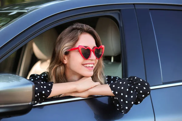 Jovem mulher bonita vestindo óculos em forma de coração no carro — Fotografia de Stock