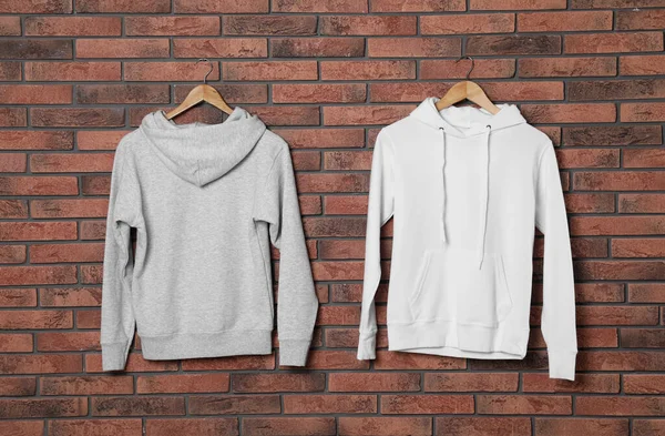 Kleer Hangers met nieuwe truien op bakstenen muur, mock up voorontwerp — Stockfoto