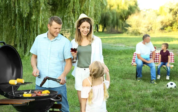 Happy family having barbecue in park on sunny day — Stock Photo, Image