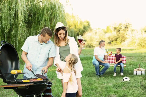 ครอบครัวที่มีความสุข มีบาร์บีคิวในสวนสาธารณะในวันที่มีแดด — ภาพถ่ายสต็อก