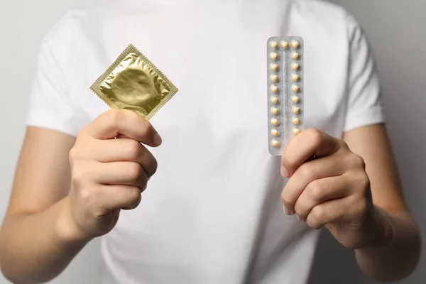Junge Frau mit Antibabypille und Kondom, Nahaufnahme. Safe-Sex-Konzept — Stockfoto