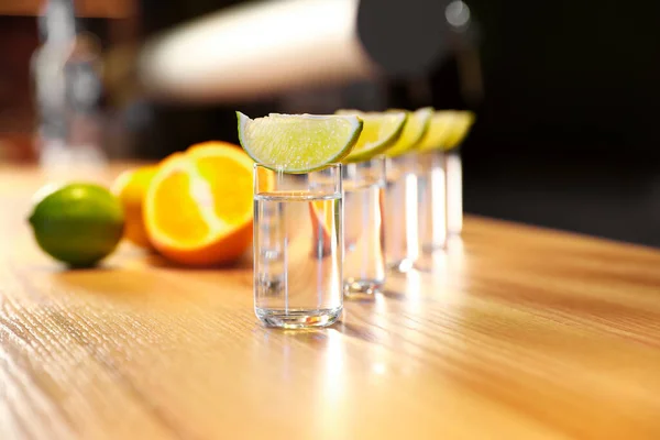 Colpi di vodka e fette di lime sul bancone del bar in legno — Foto Stock