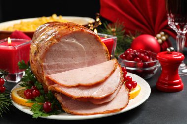 Lezzetli bir Noel jambonu, karanlık masada garnitürle servis edilir.