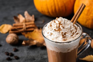 Krem şantili balkabağı aromalı latte ve gri masadaki cam bardakta tarçın çubuğu, yakın plan. Metin için boşluk