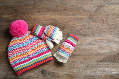 Sıcak örülmüş şapka ve tahta arka planda eldivenler, düz yatış. Metin için boşluk