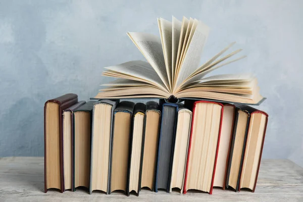 Stapel hardcover boeken op houten tafel tegen lichtblauwe achtergrond — Stockfoto