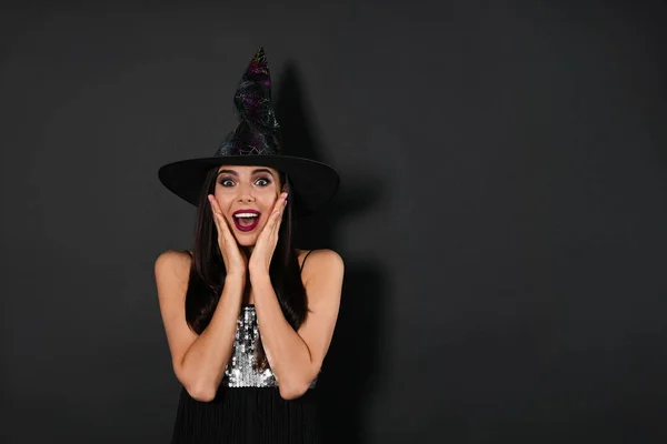 Mujer excitada vistiendo traje de bruja para la fiesta de Halloween sobre fondo negro, espacio para el texto —  Fotos de Stock