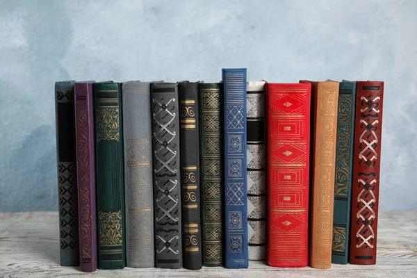 Stapel hardcover boeken op houten tafel tegen lichtblauwe achtergrond — Stockfoto
